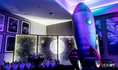 a space rocket sitting on top of a table in a room with pictures and lights