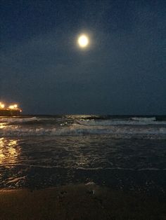 the moon is setting over the ocean with waves