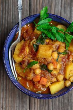 a blue bowl filled with stew and garnished with parsley on the side