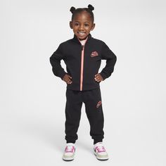 This 2-piece tracksuit is made of cotton/poly fabric with an allover knit Swoosh pattern sure to make an impression. The jacket has a standing collar with a roomy cut and full-zip closure that makes layering easy. The matching pants have a comfy stretch waistband with tapered legs and ribbed cuffs that create a cozy, secure feel. Pair this set with any Nike tank or tee to put your little one in coordinated Swoosh style they can play comfortably in. Nike Cotton Sportswear Sets, Casual Nike Tracksuit For Fall, Nike Casual Long Sleeve Tracksuit, Nike Long Sleeve Loungewear Sets, Nike Cotton Athleisure Sets, Nike Cotton Athleisure Tracksuit, Nike Cotton Sportswear Tracksuit, Nike Loungewear Sets, Nike Casual Loungewear Sets