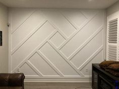 a living room with a couch, chair and wall paneled in white paint on the walls