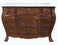 an ornately carved wooden cabinet with marble top and drawer pulls on the bottom, against a white background