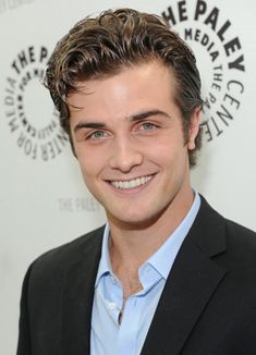 a smiling man in a suit and blue shirt is posing for the camera at an event