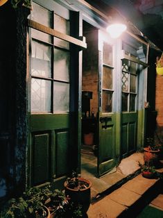 a green door is open in front of a house with potted plants on the porch