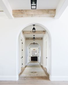 an archway leading to a living room with white walls and wood beams on the ceiling