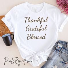 This "Thankful Grateful Blessed" T-shirt is perfect for spreading positivity and inspiration. Featuring a motivational quote, it makes a great addition to your casual wear collection. Whether you're going out for a walk or just lounging at home, this shirt will remind you to stay thankful, grateful, and blessed. It also makes a thoughtful gift for friends and loved ones who appreciate positive messages. 🌟 Elevate your wardrobe with our Unisex Classic T-Shirt, designed to be your new go-to favorite! Made from premium quality materials, this soft and breathable tee is perfect for any occasion, whether you're dressing up for a casual outing or lounging at home. 🌟Key Features: 🌟Material: Crafted from 100% Airlume combed and ring-spun cotton for unparalleled comfort. (Fabric blends may vary Inspirational Crew Neck T-shirt For Fall, White Inspirational Relaxed Fit T-shirt, Inspirational Graphic Print T-shirt For Fall, Inspirational Cotton T-shirt For Fall, Spreading Positivity, Thankful Grateful Blessed, Message Positif, Grateful Thankful Blessed, Quote Tees