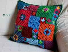 a colorful crocheted pillow sitting on top of a white couch