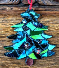 a stained glass christmas tree ornament hanging on a wooden table