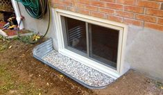 an open window on the side of a brick building next to a garden hose holder