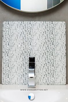 a white sink sitting under a mirror next to a wall mounted faucet in a bathroom