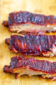 two pieces of meat sitting on top of a wooden cutting board next to each other