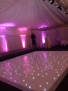 a dance floor is lit up with purple lights