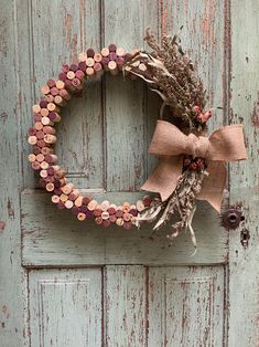 a wreath made out of wine corks is hanging on a door with a bow