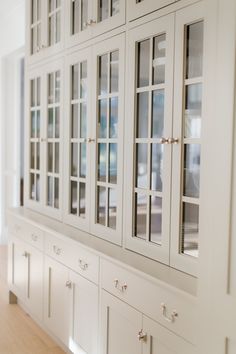 a white china cabinet with glass doors and drawers