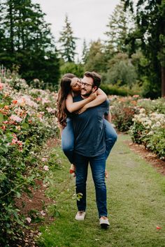 a man and woman hug in the middle of a flower garden