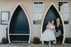 a bride and groom standing in front of some fake surfboards on the side of a building