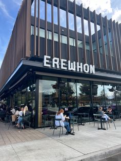 people sitting at tables in front of a restaurant with the name erewhon on it