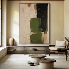 an abstract painting hangs in the middle of a room with two chairs and a coffee table