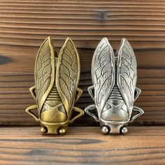 two metal objects sitting on top of a wooden table next to each other and one has wings