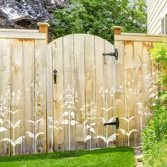 a wooden fence with white flowers painted on it and grass in the yard behind it