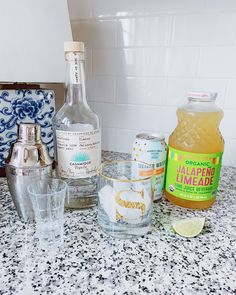 bottles and glasses on a counter top next to an ice bucket, lemon wedges, and other ingredients