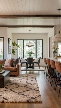 a living room filled with furniture next to a dining room table and chairs on top of a hard wood floor