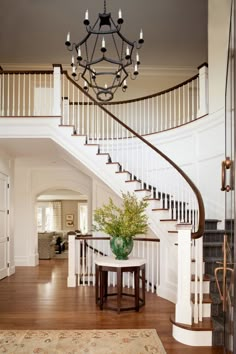 a foyer with a chandelier, table and stairs leading up to the second floor