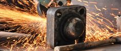 welder cutting metal with sparks coming out of the machine's back end and head