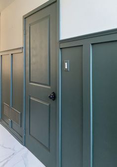 two doors are open in a hallway with marble flooring and white walls on either side