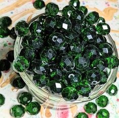 a bowl filled with green beads on top of a table