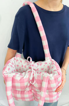 a woman is holding a pink and white checkered bag with a bow on it