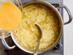 a large pot filled with yellow liquid next to a metal pan on top of a stove