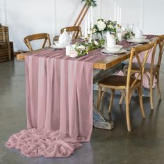 the table is set with pink linens and white flowers in vases on it