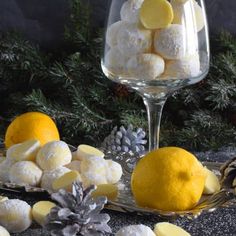 there are lemons and marshmallows in the glass next to pine cones