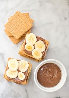 peanut butter and banana slices on crackers next to a small bowl of chocolate pudding