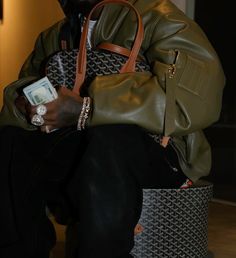 a man sitting on top of a basket holding a purse and money in his hand