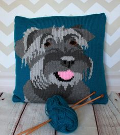 a blue pillow with a dog on it next to knitting needles