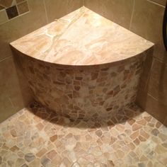 the corner of a shower with stone flooring