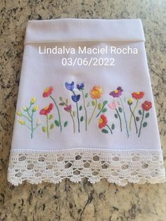 a white towel with flowers on it sitting on top of a granite counter next to a lace border