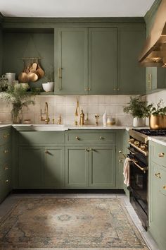 a kitchen with green cabinets and gold accents on the counter tops, along with an area rug