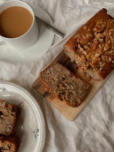 sliced loaf of banana nut bread next to a cup of coffee on a white tablecloth