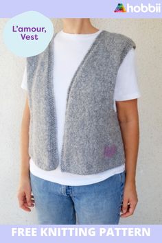 a woman standing in front of a white wall wearing a gray knitted vest and jeans