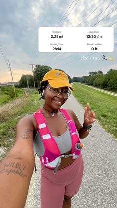 a woman in pink shorts and a yellow hat is holding her arm up to the camera