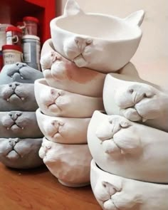 there are many white cat bowls on the table with their faces carved into it's sides