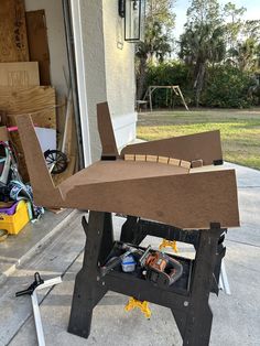 an airplane made out of cardboard sitting on top of a workbench in front of a house