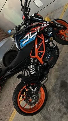 an orange and black motorcycle parked next to a car