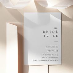 the bride to be card is laying on top of some white paper and ribbon around it