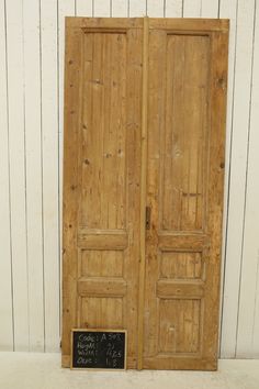 an old pair of wooden doors with chalk written on the front and side panels, against a white wall