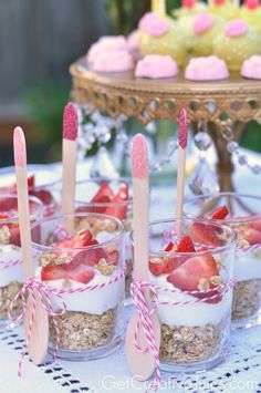 desserts with strawberries and cupcakes are arranged in small cups on a table