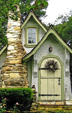 a small house with a stone chimney in the front yard